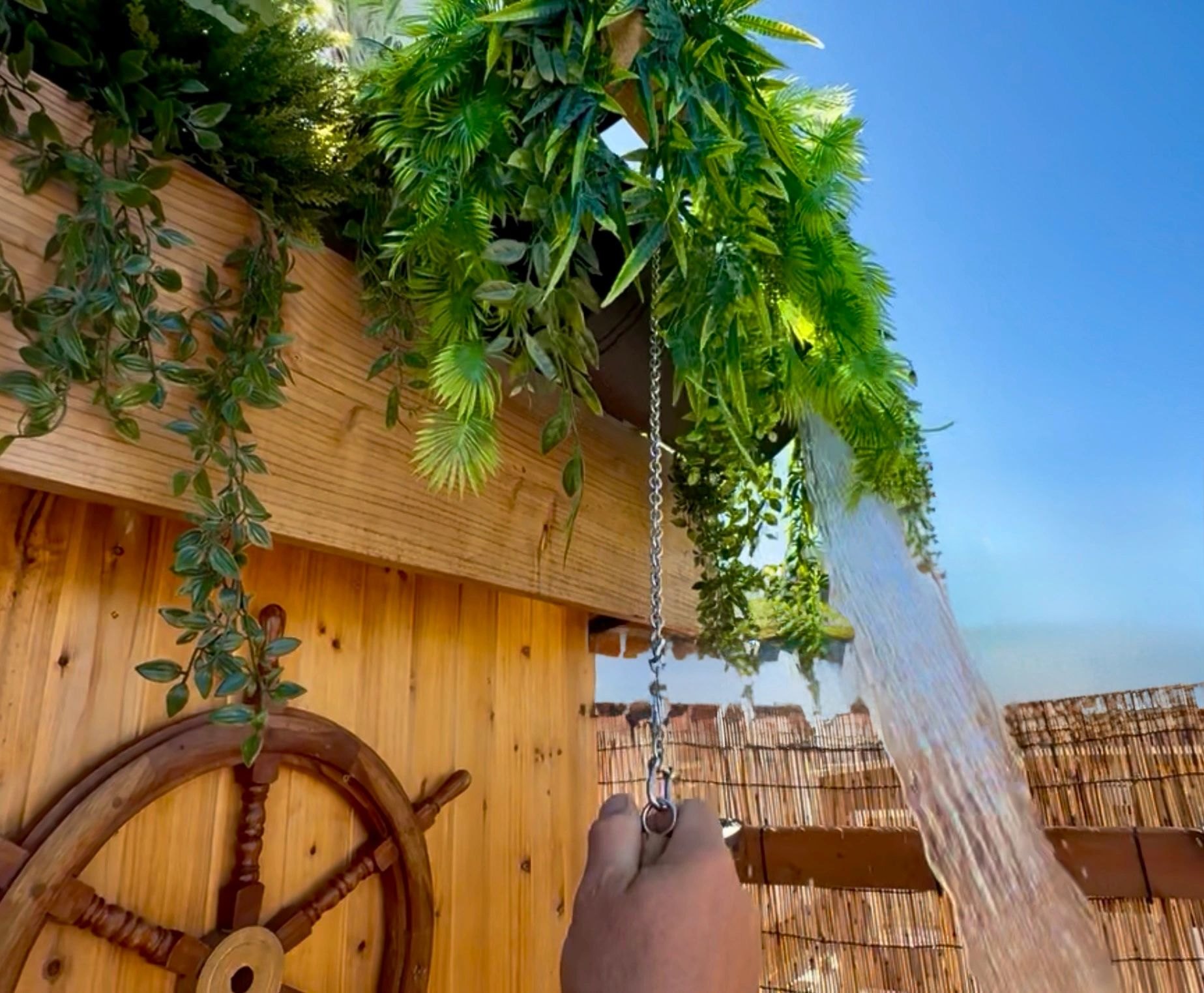 Pulling the chain on the cold bucket shower under greenery on the Banya Boat deck